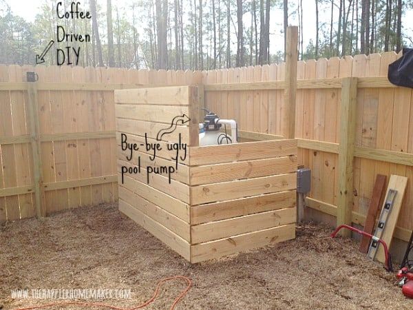 a wooden box with writing on it in the middle of a fenced in area