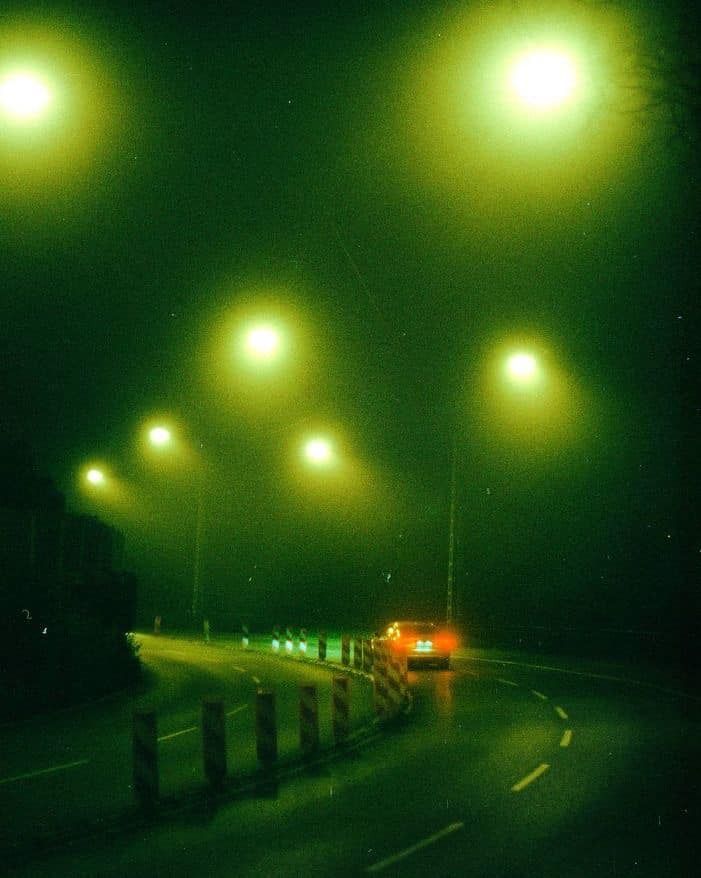 an empty street at night with green lights