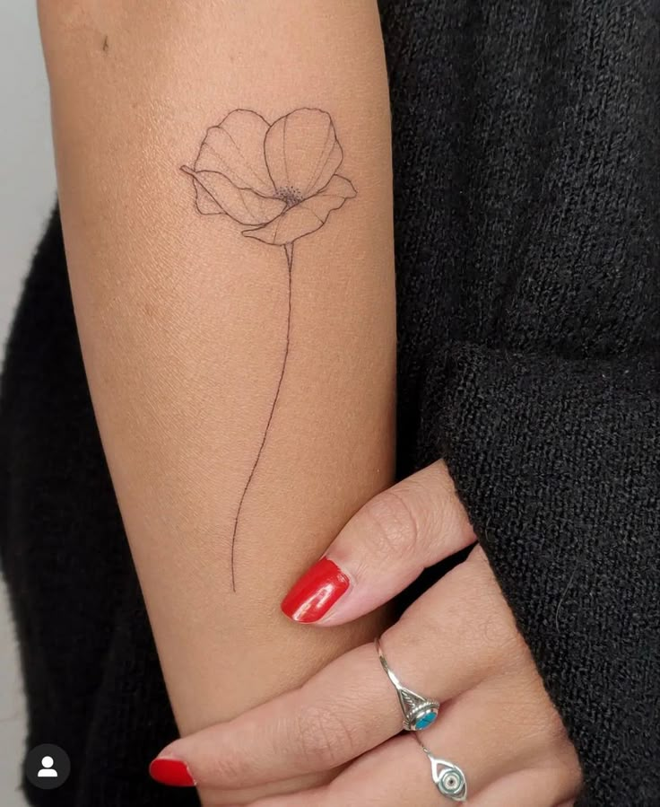 a woman's arm with a single flower tattoo on the left side of her arm