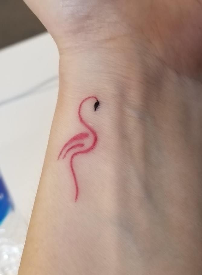 a small tattoo on the wrist of a woman's arm with a pink flamingo