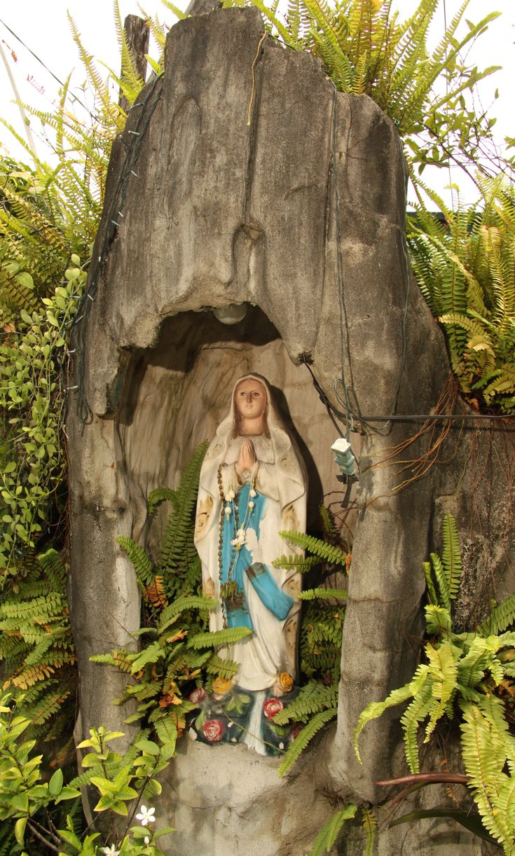 a statue of jesus surrounded by plants and rocks