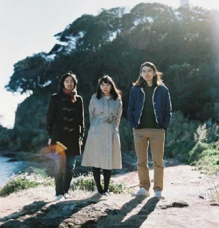 three people are standing on a hill by the water