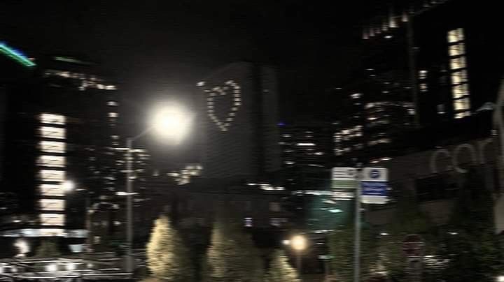 a city street at night with tall buildings in the background