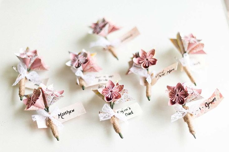 small pink and white flowers are placed on top of each other with name tags attached to them