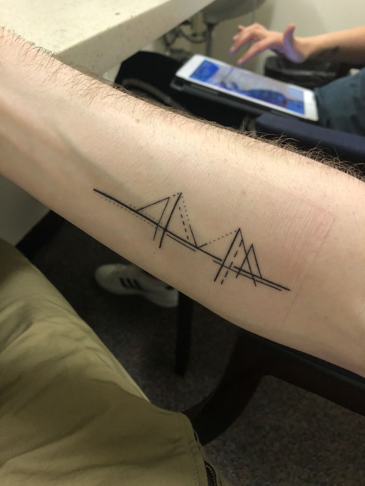 a man with a tattoo on his arm that has three triangles in the same direction