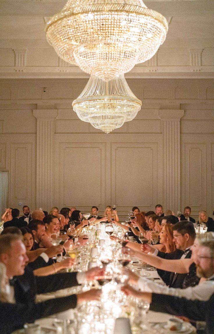 a group of people sitting at a long table with wine glasses in front of them