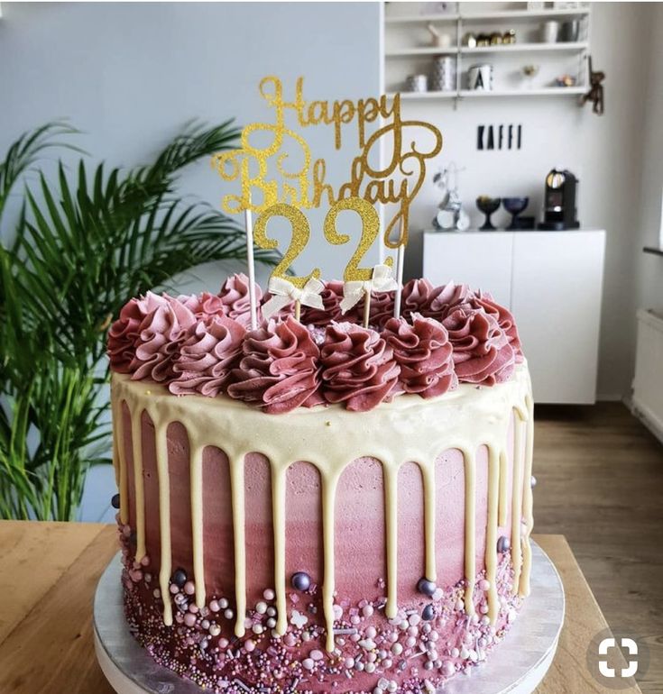 a birthday cake decorated with pink and gold icing