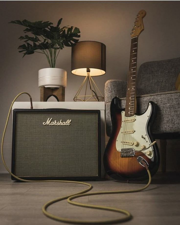 a guitar and amp sitting on the floor next to a lamp