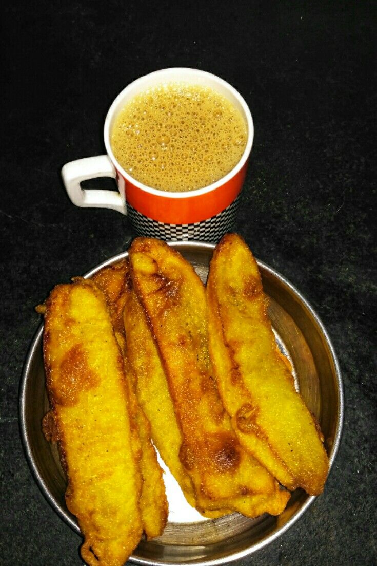 some fried food on a plate next to a cup of coffee