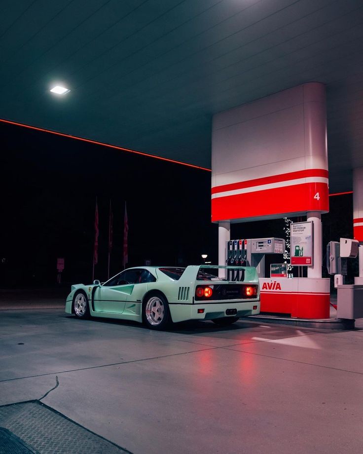 a green sports car parked in front of a gas station