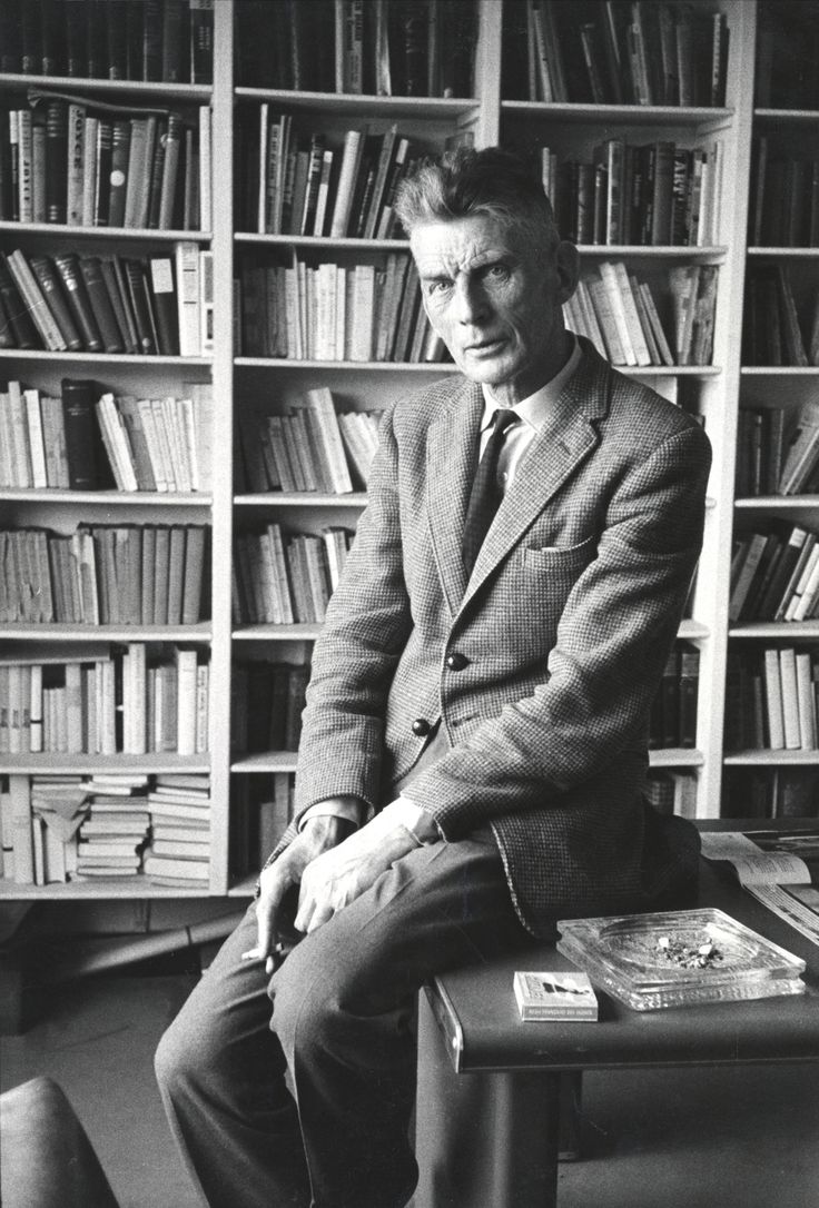 a man sitting on top of a table in front of a book shelf filled with books