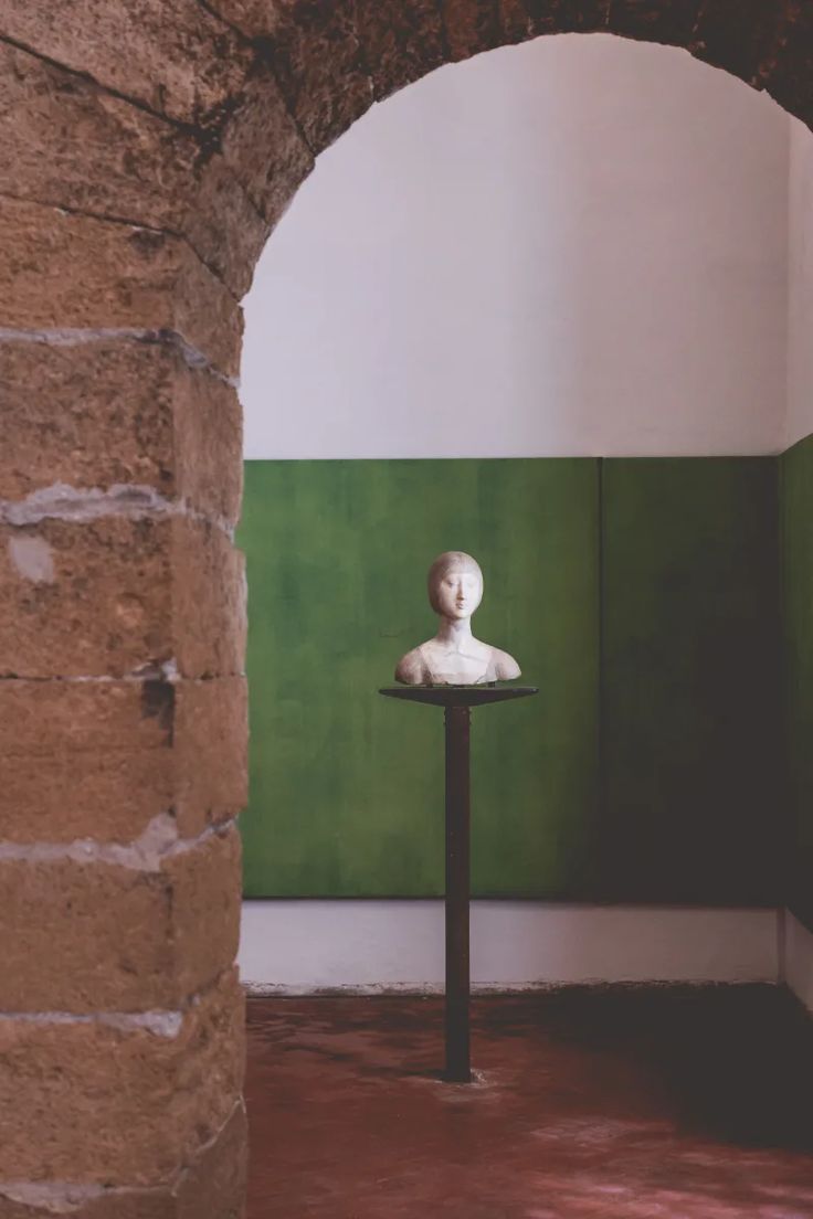 a white busturine sitting on top of a table in a room with green walls