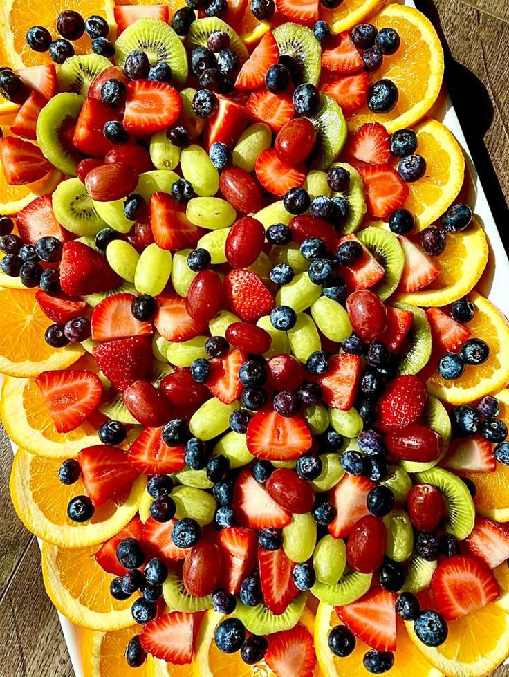 a platter filled with sliced fruit on top of a wooden table