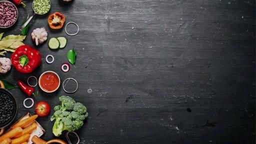 an assortment of vegetables and sauces laid out on a black surface with space for text