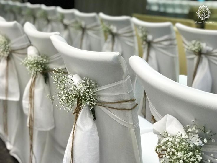 rows of white chairs with sashes and flowers tied to the back, all lined up