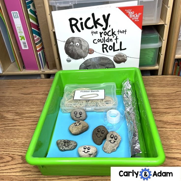 rocks are placed in a green tray on the table next to a book and some other items