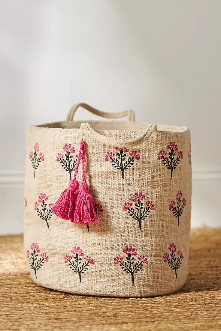 a handbag with pink flowers and tassels on it sitting on a rug