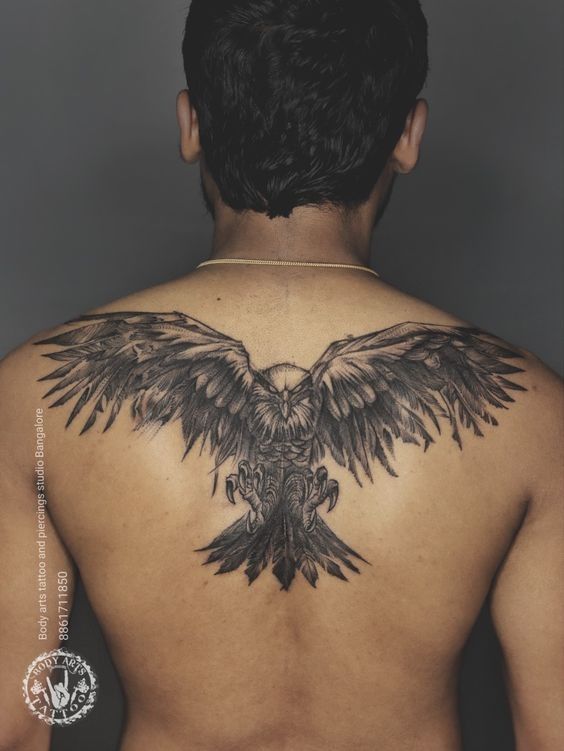 the back of a man's upper body with an eagle tattoo on his chest