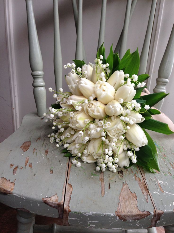 a bouquet of white flowers sitting on top of a wooden chair