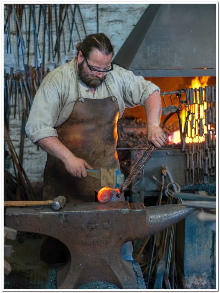 a man working in a blacksmith with an iron hammer