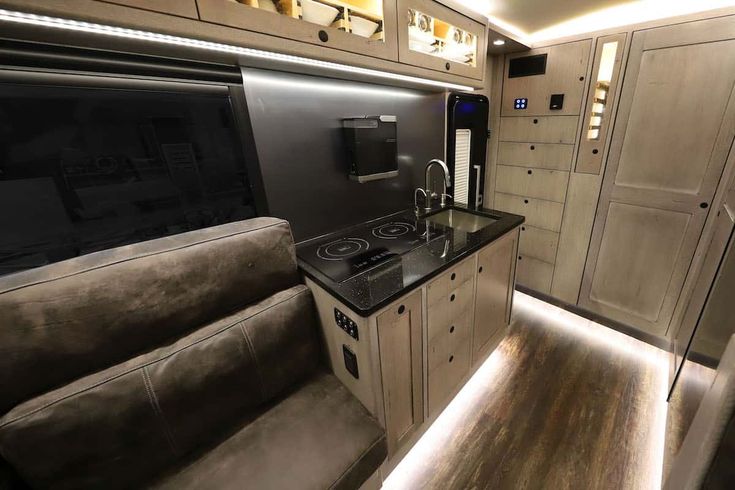 the interior of an rv with wood flooring and black counter tops, including a stove top