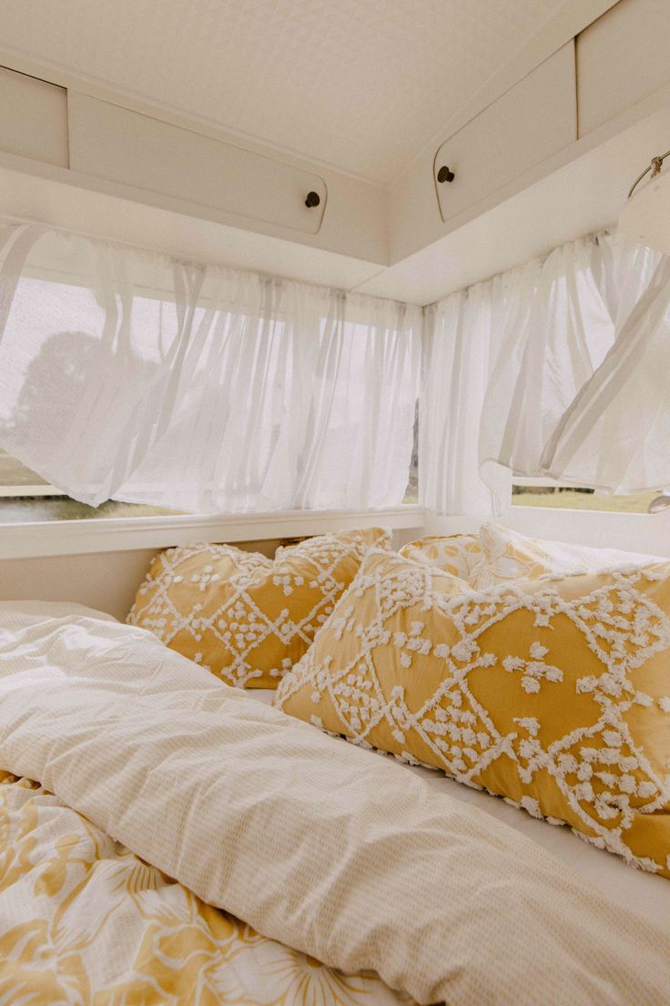 there is a bed with yellow and white pillows in the room next to the window