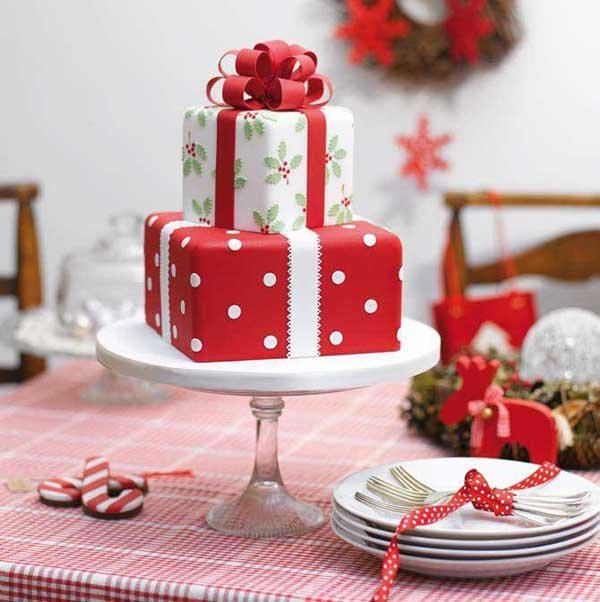 a red and white cake with presents on it sitting on a table next to plates