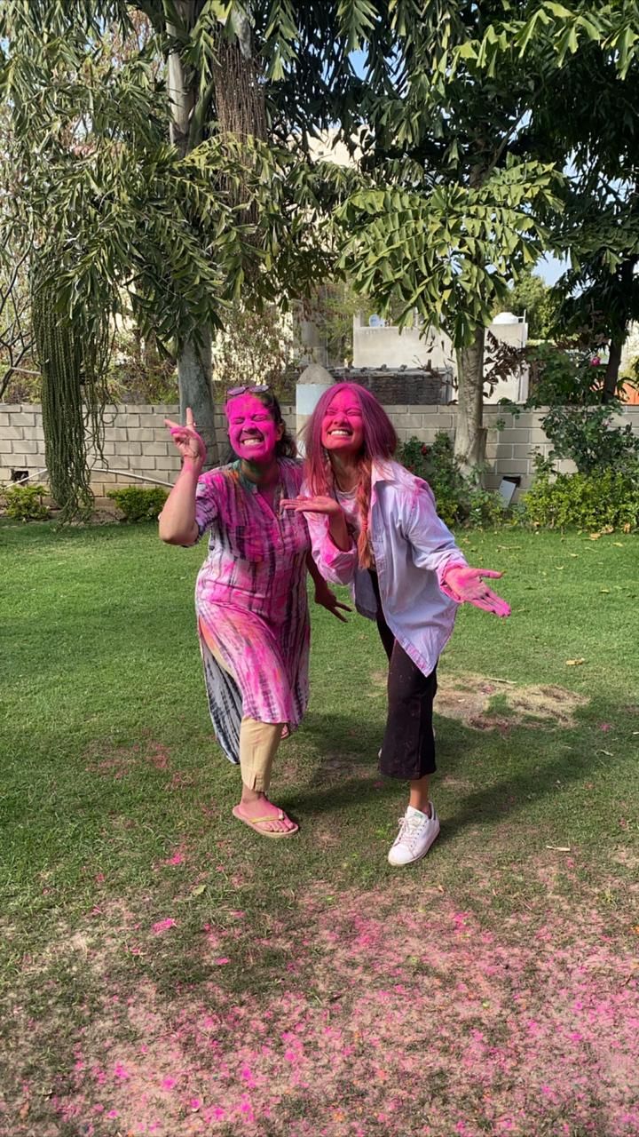 two girls with pink paint on their faces posing for the camera in front of some trees