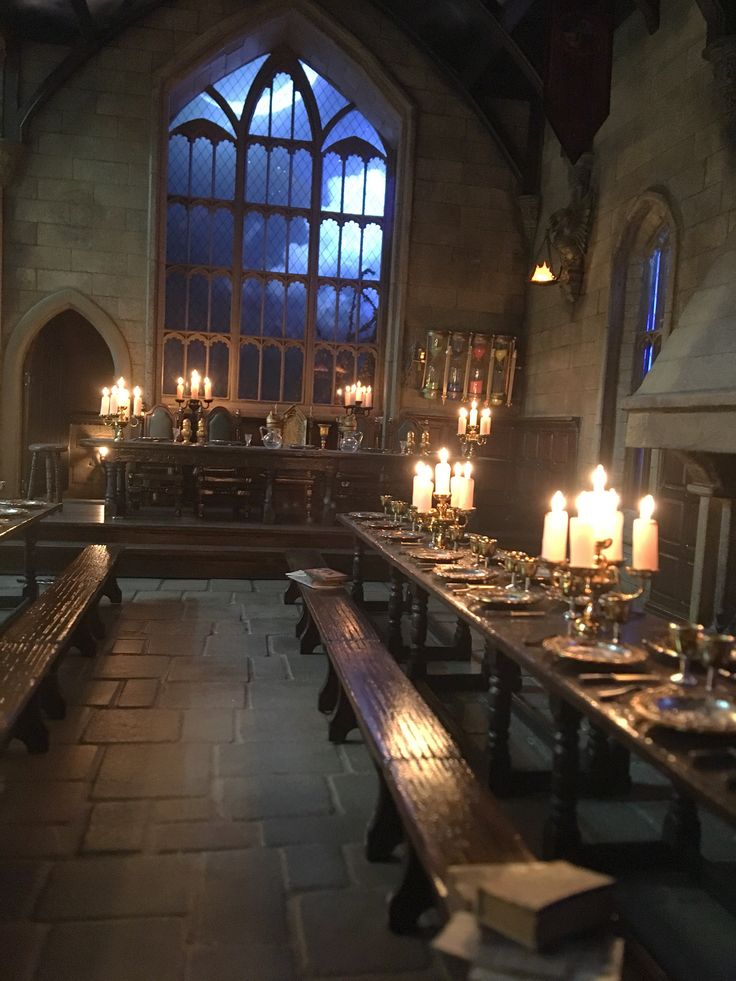 a long table with candles on it in front of a large window filled with windows