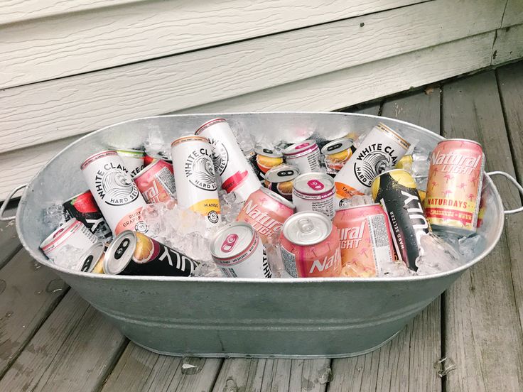 a metal tub filled with lots of different types of sodas and cans on top of a wooden deck