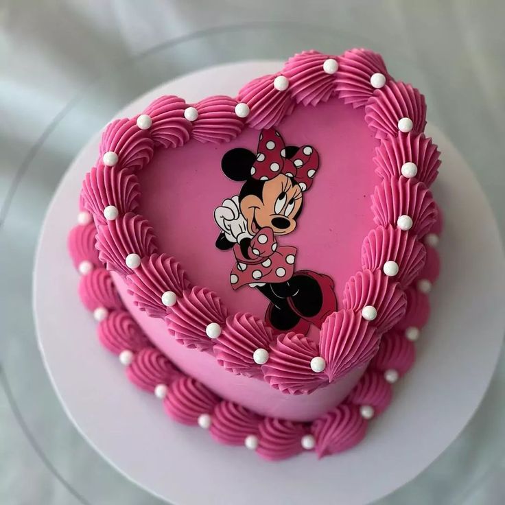 a heart shaped cake with minnie mouse on top