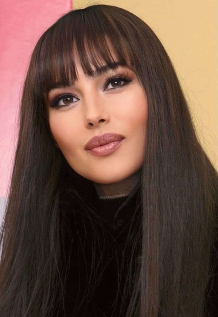 a woman with long brown hair and bangs wearing a black turtle neck sweater is looking at the camera