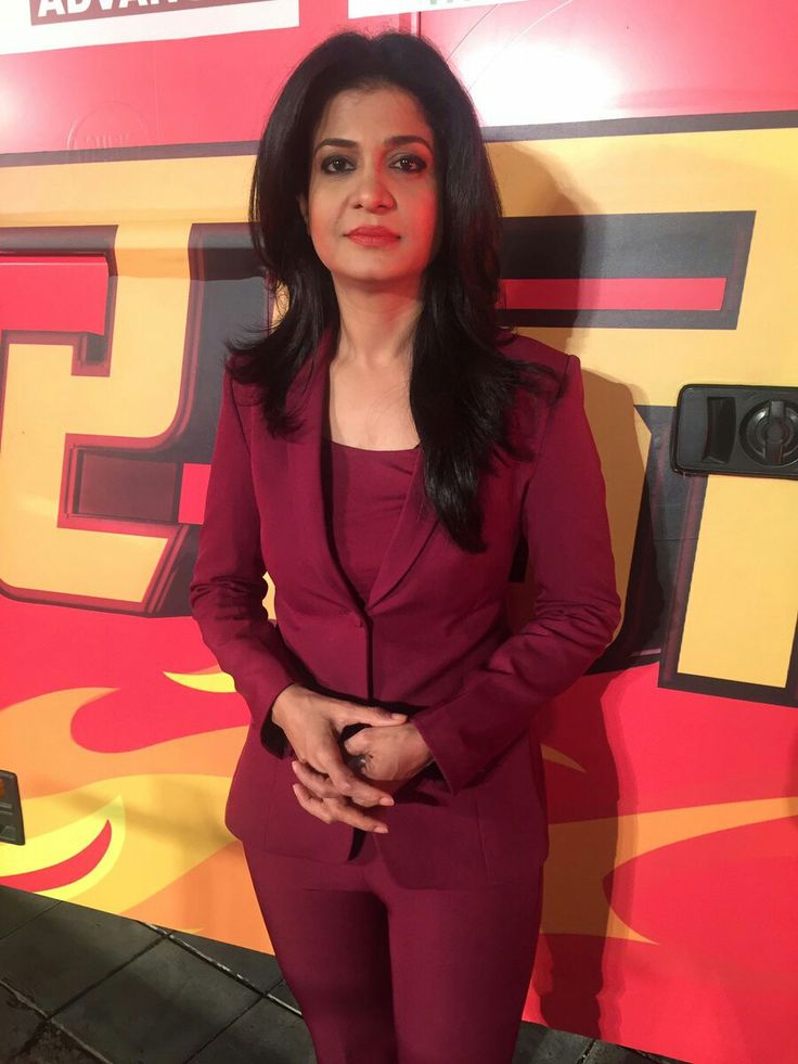 a woman standing in front of a red and yellow wall with her hands on her hips