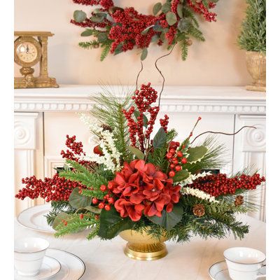 a christmas centerpiece with red flowers and greenery