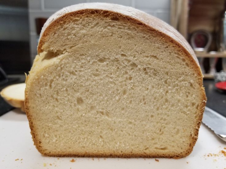 a loaf of white bread sitting on top of a cutting board next to a knife