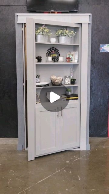 a tv is on top of a bookcase in a room with grey walls and flooring