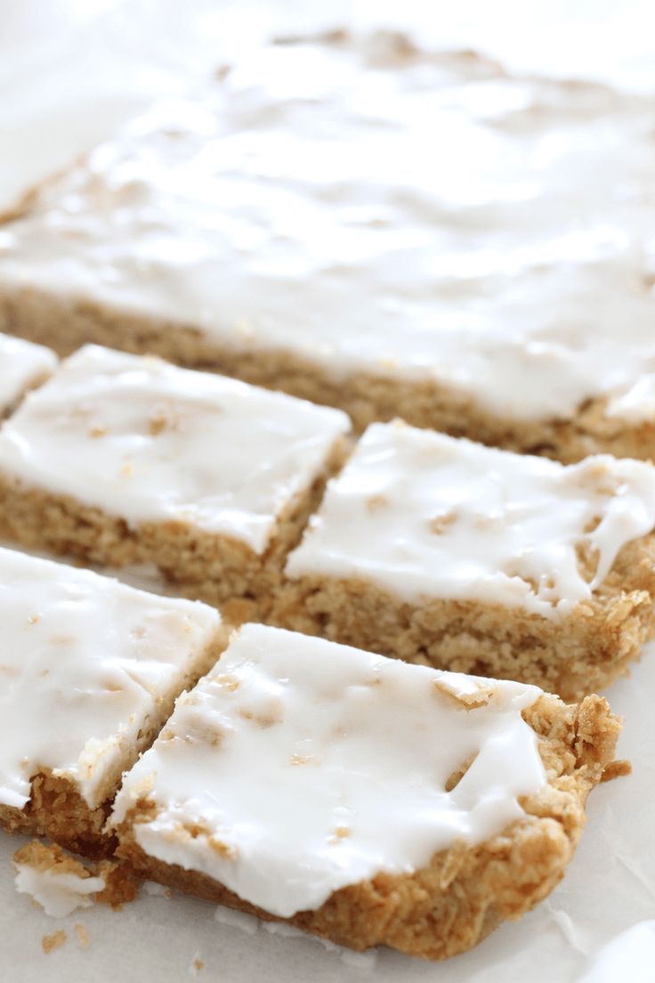 there are several pieces of cake on the table with white frosting and one is cut into squares