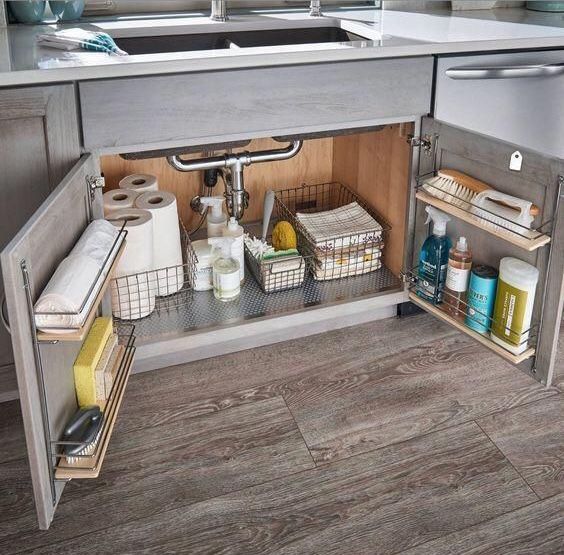 an open cabinet in a kitchen with items on the shelves and under it's sink