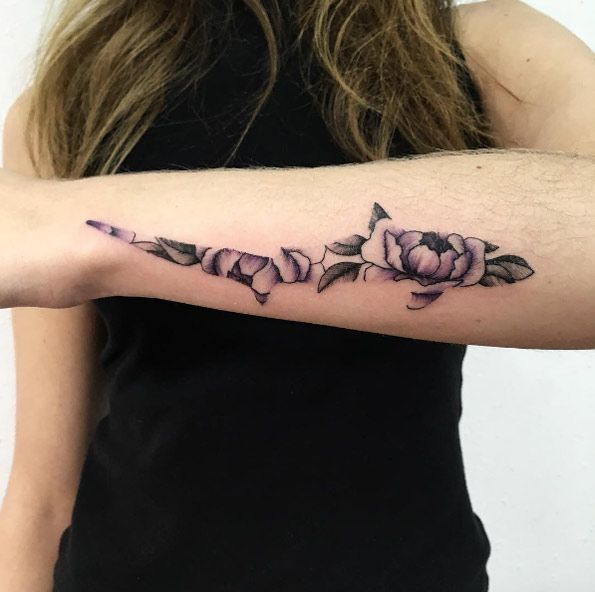 a woman with a black and white tattoo on her arm that has pink flowers in it