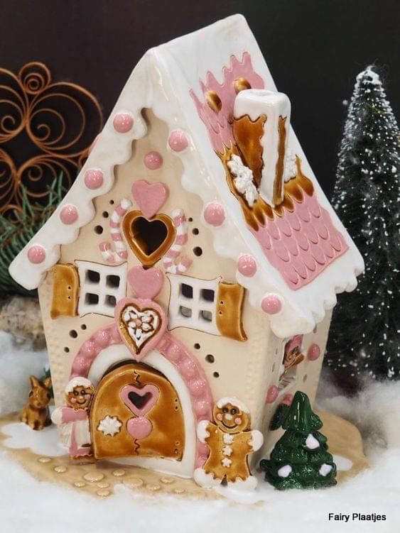 a gingerbread house is decorated with pink and gold decorations on it's roof