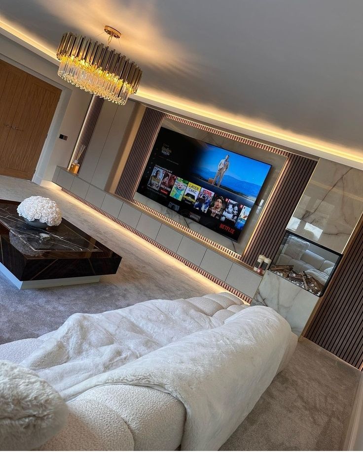 a large white couch sitting in a living room next to a flat screen tv on a wall