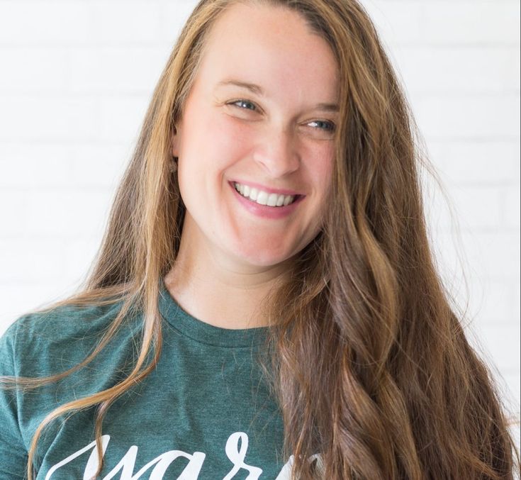 a girl with long hair smiling and wearing a green t - shirt that says year after march