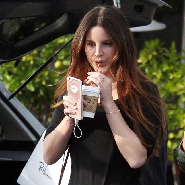 a woman is holding her cell phone and looking at the camera while she's getting ready to go shopping