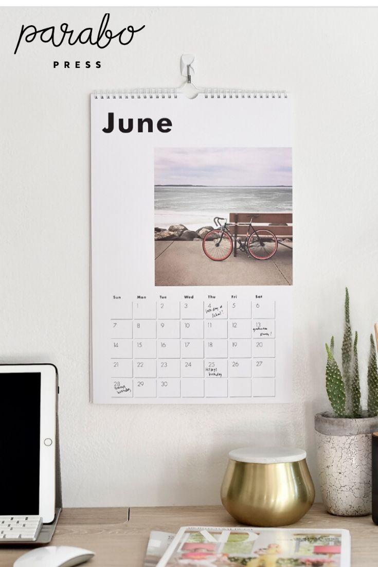 a desk with a calendar, phone and cactus