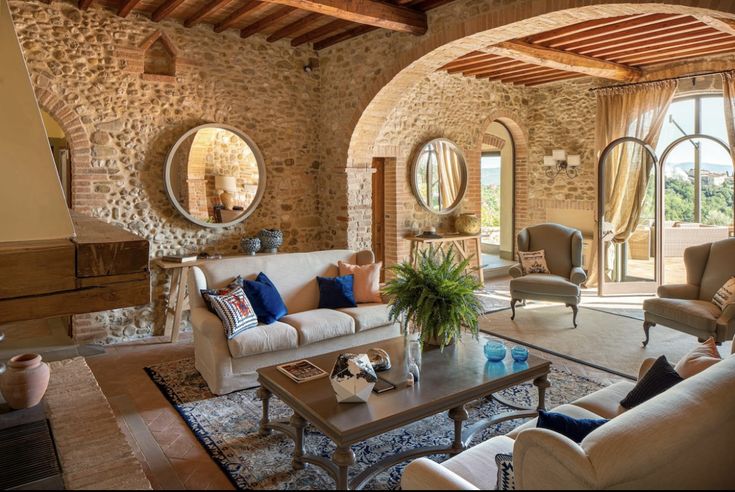 a living room with couches, chairs and tables in front of an arched doorway