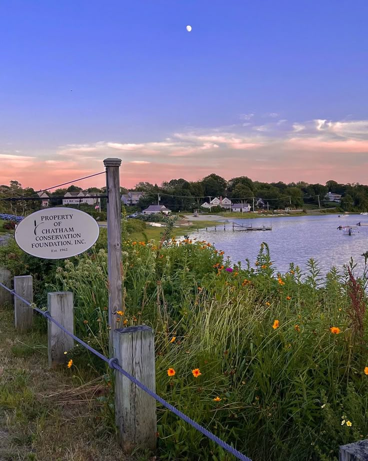 a sign is posted on the side of a fence next to a body of water