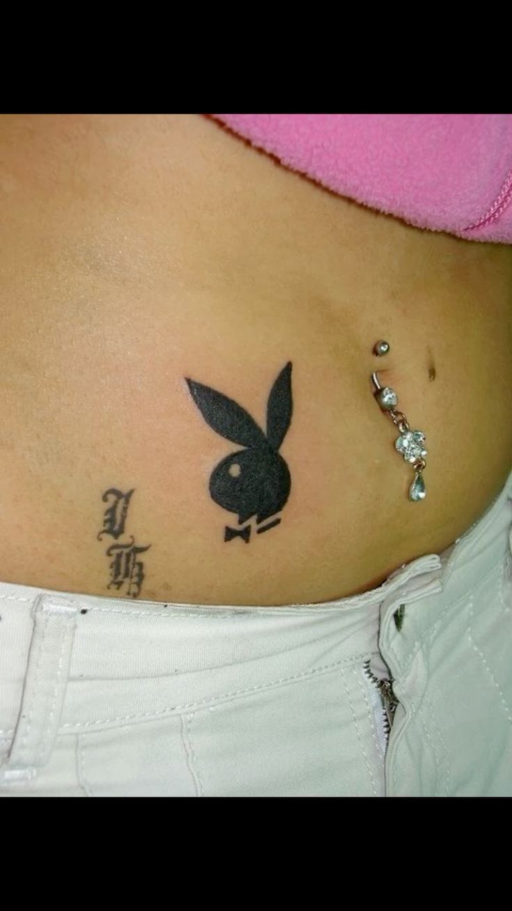 a woman's stomach with a rabbit tattoo on her belly and an ear piercing