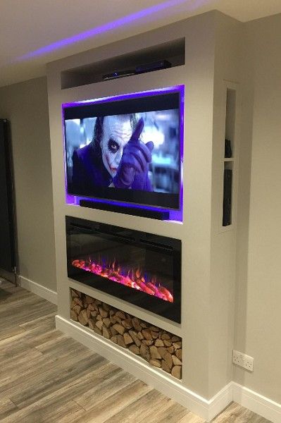 a television mounted on the wall above a fire place in a room with wood flooring