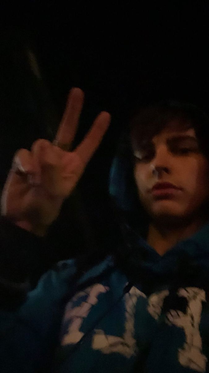 a young man making the v sign with his hand while sitting in a car at night