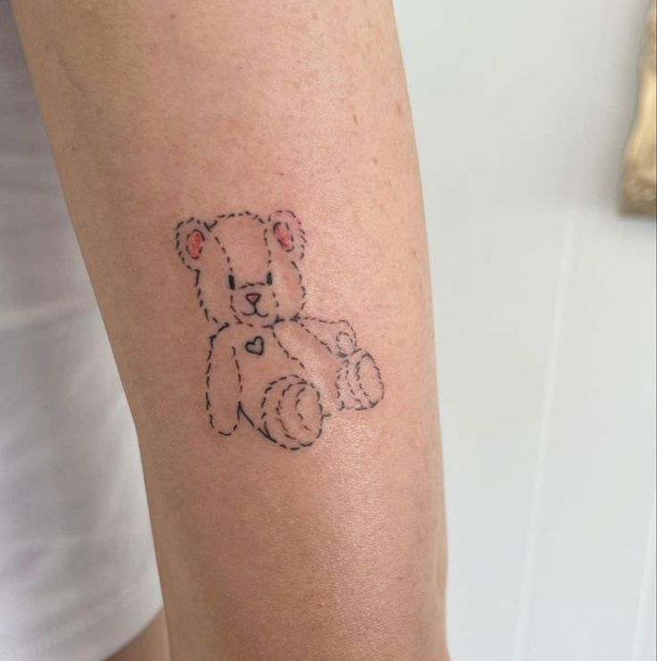 a small teddy bear tattoo on the arm